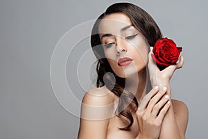 Beautiful brunette woman with red lipstick on lips. Close-up girl with rose.