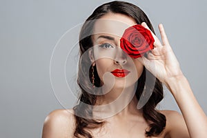 Beautiful brunette woman with red lipstick on lips. Close-up girl with rose.