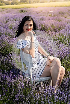 Beautiful brunette woman with red lipstick posing near lavender field