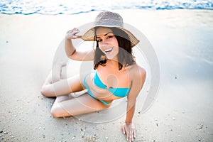 Beautiful brunette woman sitting on sandy beach and smiling, Having fun on holiday vacation on the seaside, enjoying summer