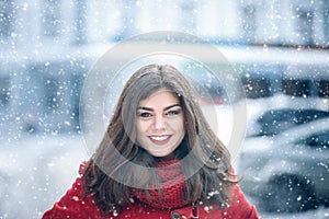 Beautiful brunette woman smiling and rejoices to snow at dte city street