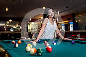 Beautiful brunette woman standing behind billiard table