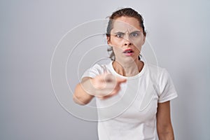 Beautiful brunette woman standing over isolated background pointing displeased and frustrated to the camera, angry and furious