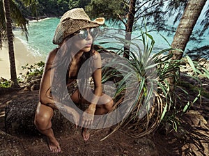 Beautiful brunette woman with straw hat and sunglasses in tropical forest