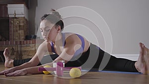 Beautiful brunette woman stretching on matt. Confident young girl sitting on the twine. Healthy lifestyle, sport