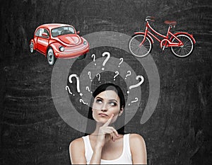 A beautiful brunette woman is trying to chose the most suitable way for travelling or commuting. Two sketches of a car and a bicyc