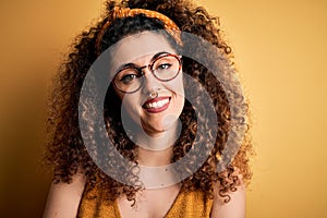 Beautiful brunette woman on vacation with curly hair and piercing wearing glasses and diadem happy face smiling with crossed arms