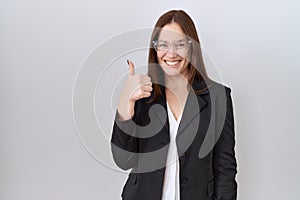 Beautiful brunette woman wearing business jacket and glasses doing happy thumbs up gesture with hand