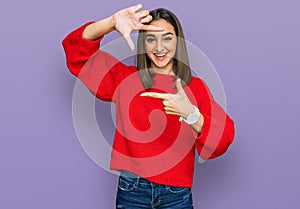 Beautiful brunette woman wearing casual winter sweater smiling making frame with hands and fingers with happy face