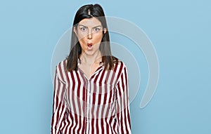 Beautiful brunette woman wearing striped shirt afraid and shocked with surprise expression, fear and excited face