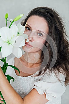 Beautiful brunette woman in white summer dress with beautiful flower