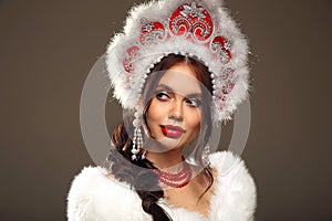 Beautiful brunette woman winter portrait in fur coat and kokoshnik (woman's headdress in old Russia).