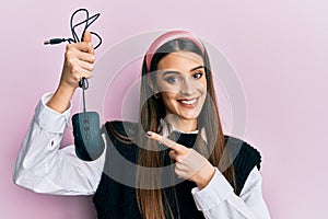 Beautiful brunette young woman holding computer mouse device smiling happy pointing with hand and finger