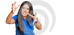 Beautiful brunette young woman wearing casual clothes shouting frustrated with rage, hands trying to strangle, yelling mad