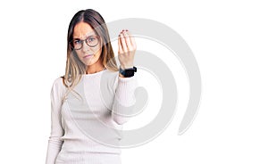 Beautiful brunette young woman wearing casual white sweater and glasses doing italian gesture with hand and fingers confident