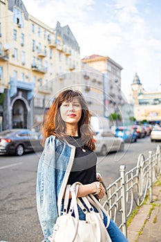 Beautiful brunette young woman wearing jeans suit and walking in the european street.
