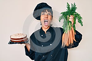 Beautiful brunettte woman chef cooking carrot cake angry and mad screaming frustrated and furious, shouting with anger looking up