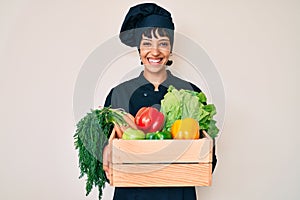 Beautiful brunettte woman chef holding fresh veggetables smiling with a happy and cool smile on face