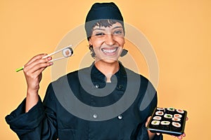 Beautiful brunettte woman chef holding sushi using chopsticks smiling with a happy and cool smile on face