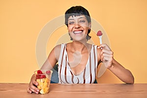 Beautiful brunettte woman eating fresh and healthy fruit smiling with a happy and cool smile on face