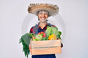 Beautiful brunettte woman wearing farmer clothes holding vegetables smiling with a happy and cool smile on face