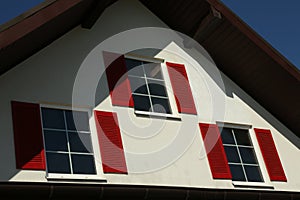 Beautiful building with windows and red shutters on day