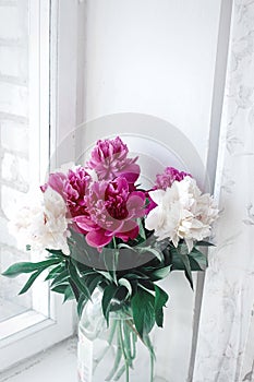 Beautiful bunch of peonies in vase on wooden white window sill b