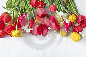 Beautiful bunch of red, yellow tulips on white wooden background.