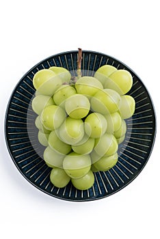 Beautiful a bunch of Shine Muscat green grape on a blue plate isolated on white background