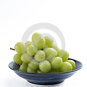 Beautiful a bunch of Shine Muscat green grape on a blue plate isolated on white background