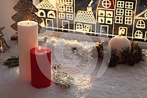 Beautiful burning candles with Christmas decor near window, space for text