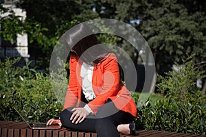 Beautiful business brunette woman works on laptop online in the park photo