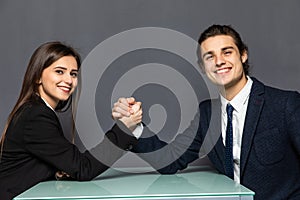 Beautiful business couple doing arm wrestling challenge isolated on gray background