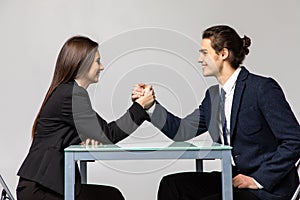 Beautiful business couple doing arm wrestling challenge isolated on white background