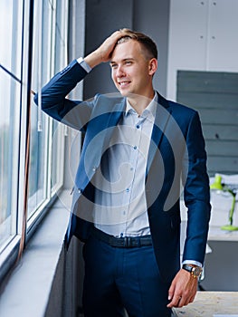 Beautiful business man looking in the window on a blurred background. Business concept. Copy space.