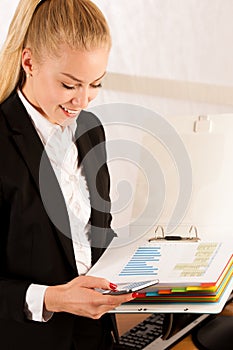 Beautiful business woamn talks on smart phona and holds a folder