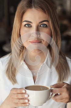 Beautiful business woman 30-40 years old drinking a cup of coffee in a cafe