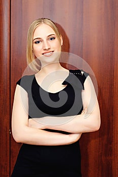 Beautiful business woman blond girl is standing on the background of a door in the office