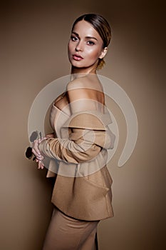Beautiful business woman in a business dress and glasses on a brown background in the studio