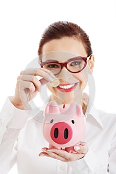 Beautiful business woman with coin and piggy- bank.