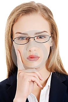 Beautiful business woman in eyeglasses with finger on her cheek.