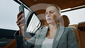 Beautiful businesswoman having video call at car. Focused woman touching face