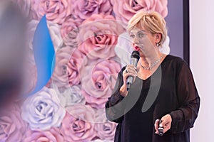 Beautiful business woman with microphone in her hand speaking at the  conference or seminar