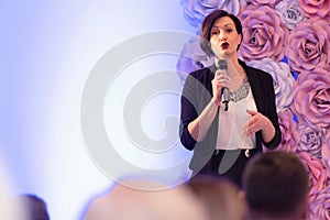 Beautiful business woman with microphone in her hand speaking at the  conference or seminar