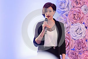 Beautiful business woman with microphone in her hand speaking at the  conference or seminar