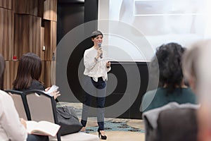 Beautiful business woman with microphone in her hand speaking at the  conference or seminar