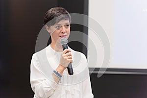 Beautiful business woman with microphone in her hand speaking at the  conference or seminar