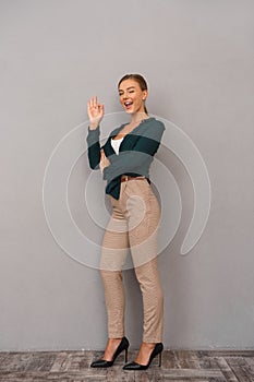 Beautiful business woman posing isolated over grey wall background showing okay gesture.