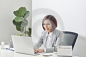 Beautiful business woman smile sitting at the desk working using laptop looking at screen typing on laptop over white background