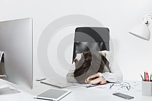 Beautiful business woman in suit and glasses working at computer with documents in light office